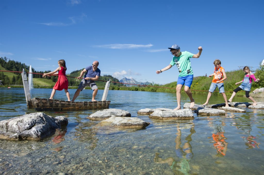 Kinder laufen über Steine in einem seichten See